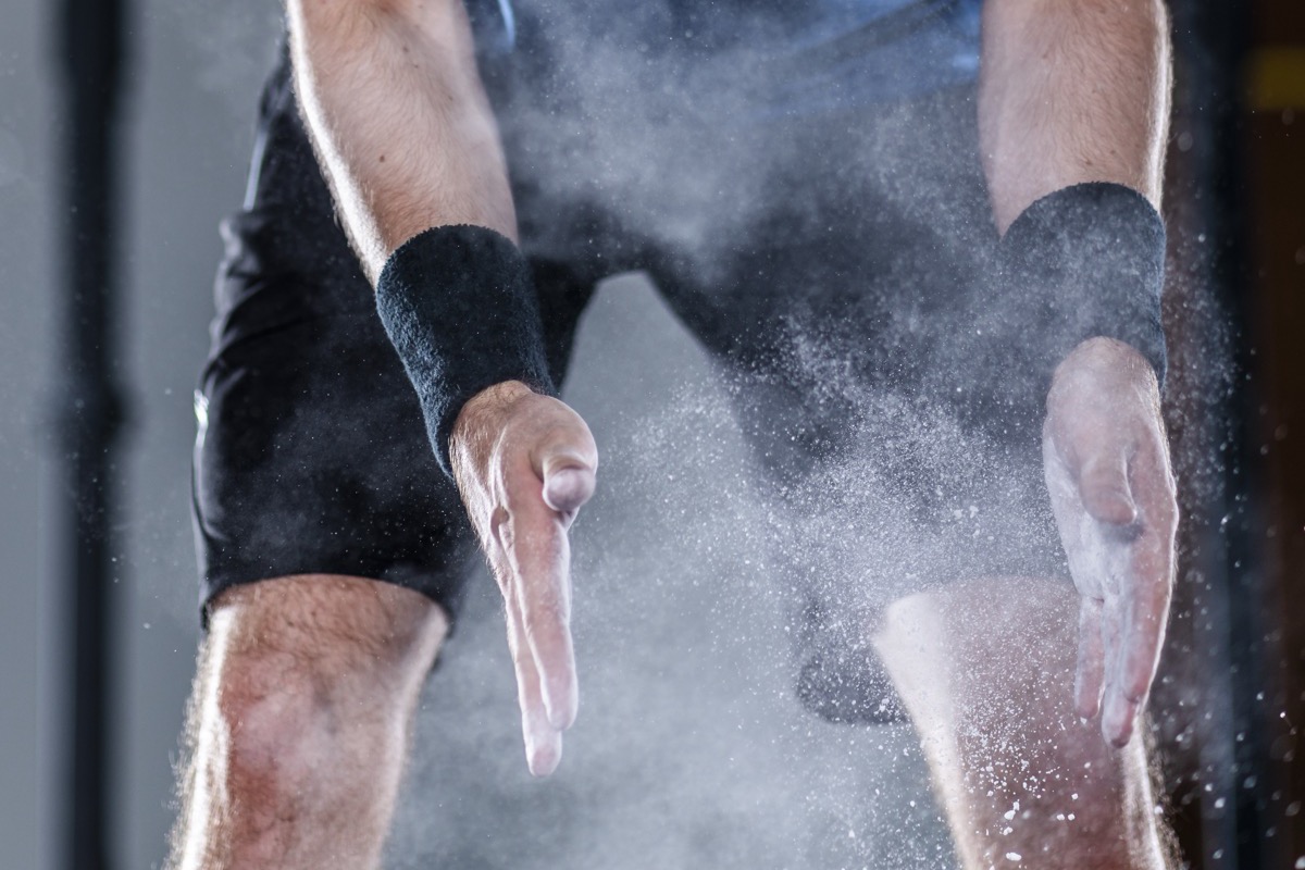 An athlete clapping chalk between their hands before a lift
