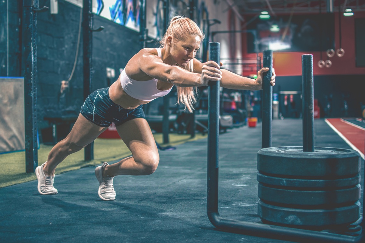 An athlete pushing a weighted sled across a gym floor